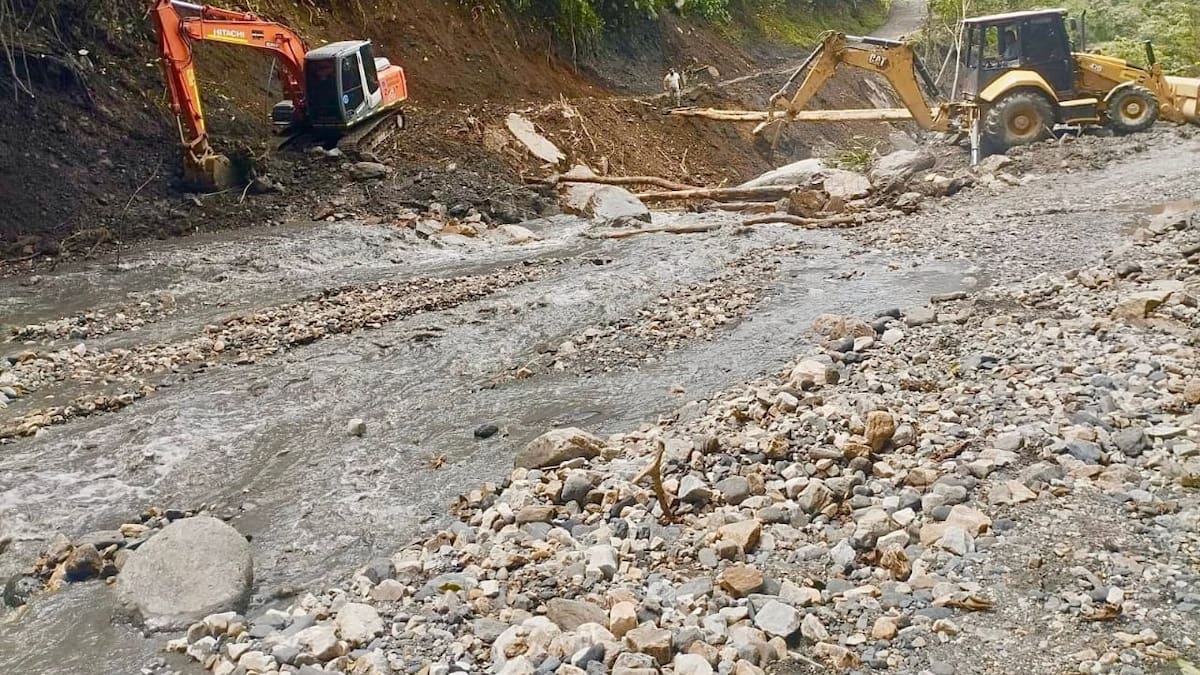 Excavadora y retroexcavadora remueven tierra y escombros de un deslizamiento junto a un río en Boyacá