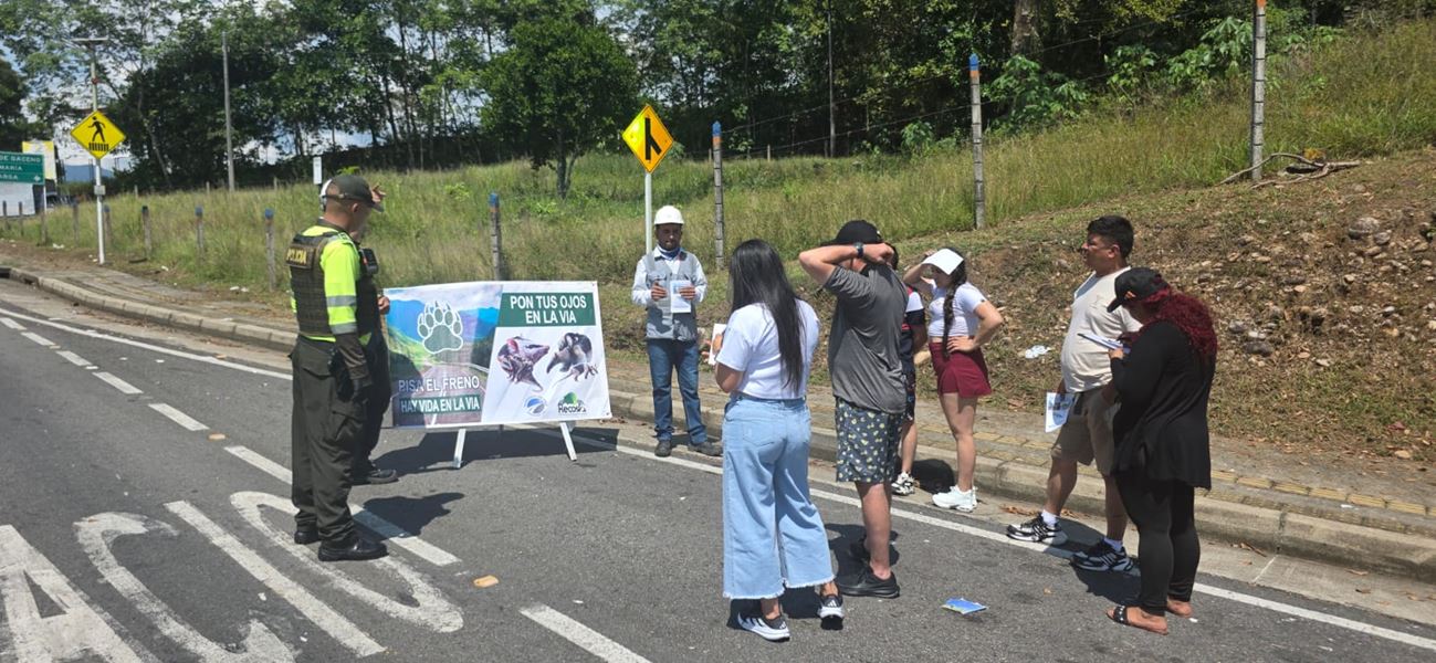 Un policía, un trabajador con casco y viajeros junto a un aviso de protección de fauna con el mensaje «Pon tus ojos en la vía»