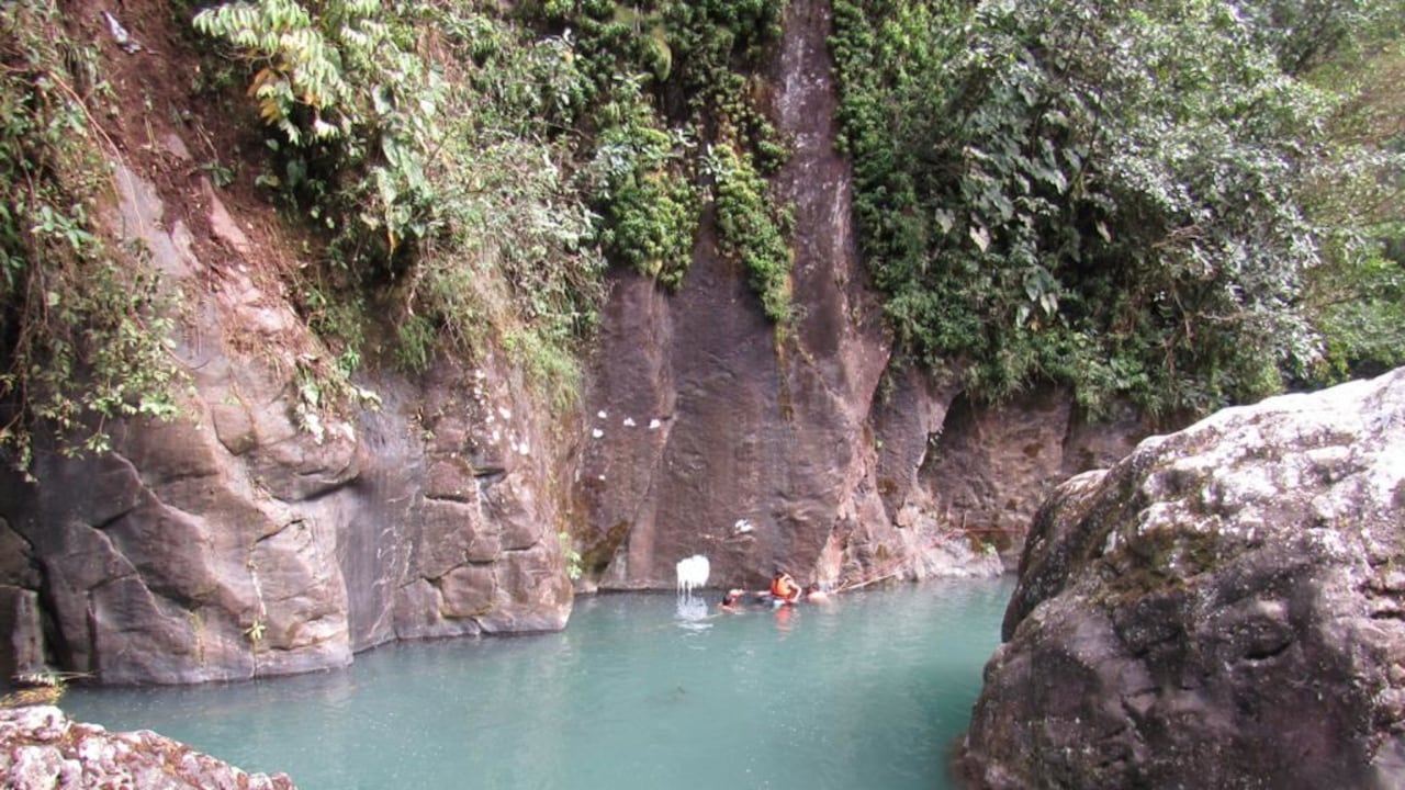 Bañistas en un pozo de agua turquesa rodeado de paredes de roca y vegetación, imagen del artículo de Semana sobre el Pozo la Calavera de Santa María