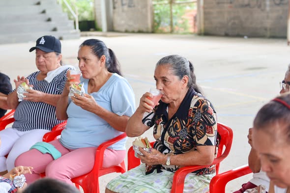 Adultas mayores de San Luis de Gaceno comparten un refrigerio en sillas plásticas rojas