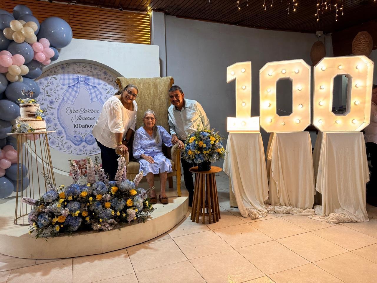 María Carlina Jiménez celebra sus 100 años en Villanueva, junto a dos acompañantes y un número 100 iluminado