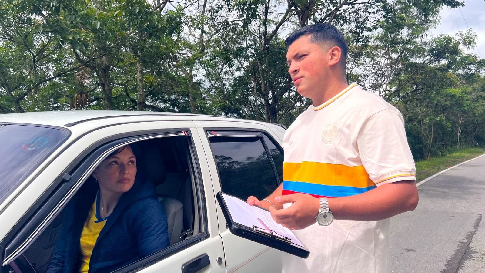 Un funcionario con una planilla habla con una conductora al borde de la vía durante la jornada de sensibilización en Guateque