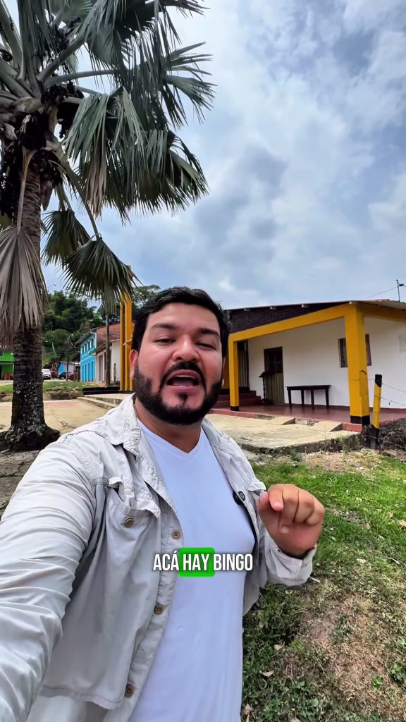 Hombre graba un video en el centro poblado de Horizontes, San Luis de Gaceno, frente a una palma y una casa de columnas amarillas