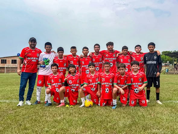 Jugadores de la Escuela de Fútbol San Luis de Gaceno y un integrante del cuerpo técnico posan en una cancha de césped