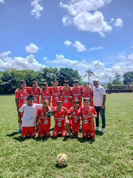 Jugadores de la Escuela de Fútbol San Luis de Gaceno con uniforme rojo posan en una cancha de césped