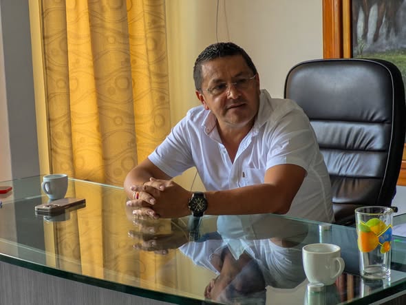 Hombre sentado ante un escritorio de vidrio en una oficina, imagen de la Alcaldía sobre la reunión con la ANH