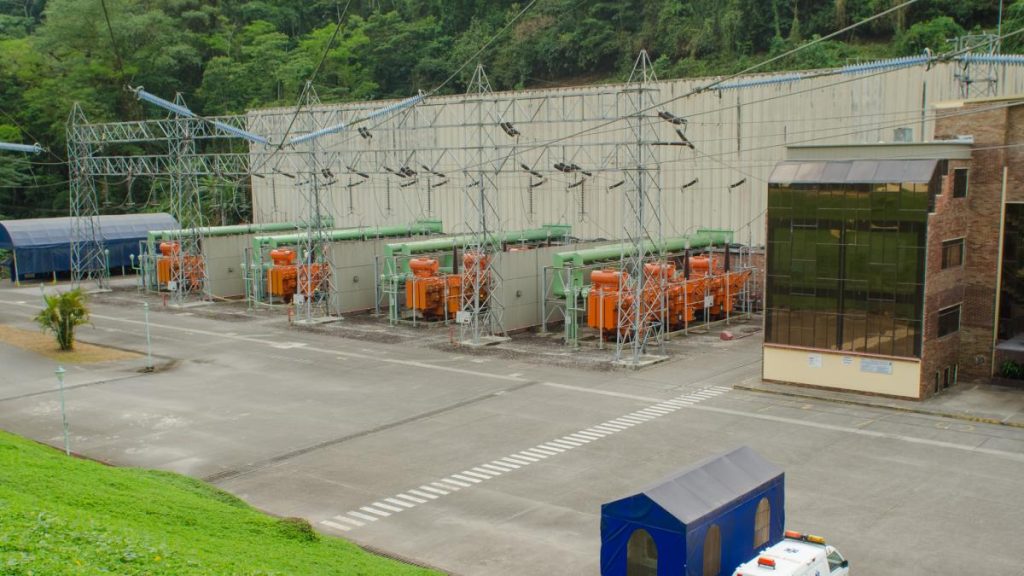 Subestación eléctrica con transformadores naranjas y torres metálicas al pie de una montaña, en una imagen de archivo de Portafolio