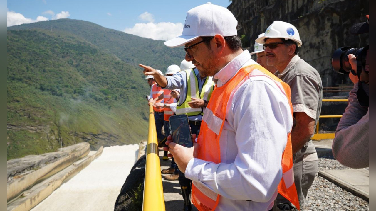 Funcionarios con cascos observan el vertedero de una hidroeléctrica, vigilancia previa al riesgo de racionamiento de energía