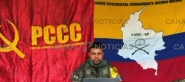 Hombre con uniforme camuflado lee un comunicado frente a banderas de las disidencias de las FARC y del PCCC