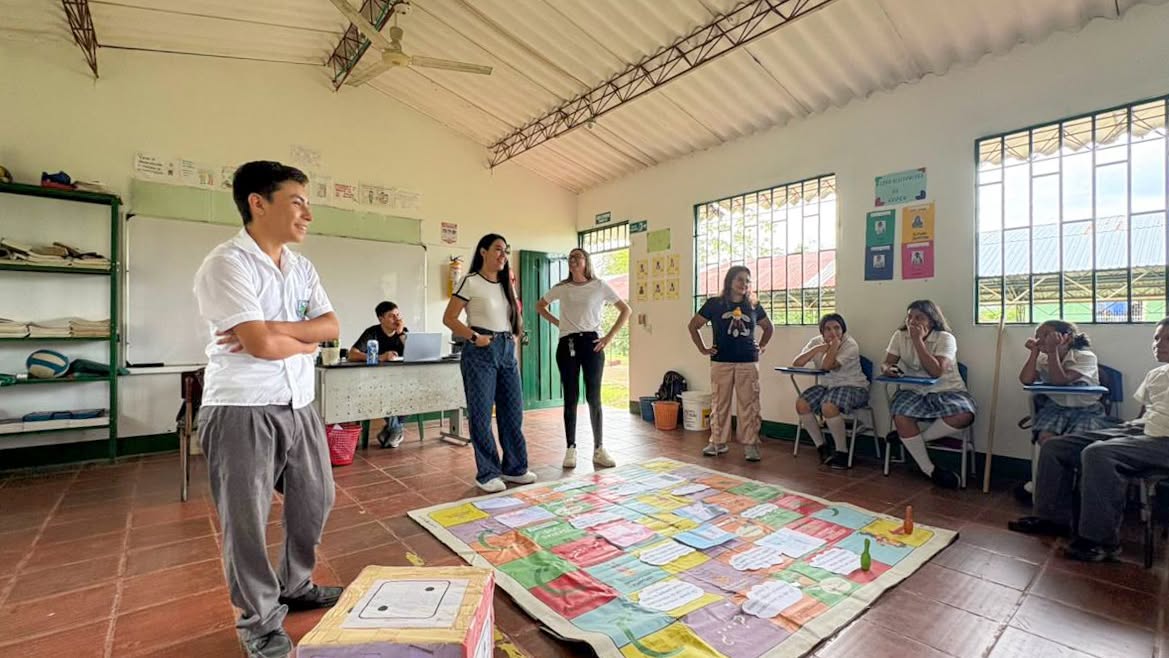 Estudiantes y facilitadoras alrededor de un juego de mesa gigante en un taller de la Comisaría de Familia en San Luis de Gaceno