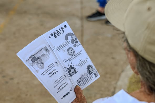 Asistente lee un folleto sobre los tipos de violencia intrafamiliar en la jornada de la Comisaría en Santa Teresa, San Luis de Gaceno