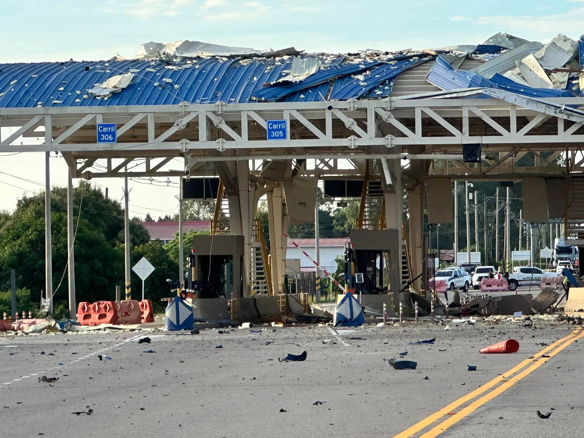 Casetas destruidas de los carriles 305 y 306 del peaje San Pedro y patrullas de la Policía al fondo
