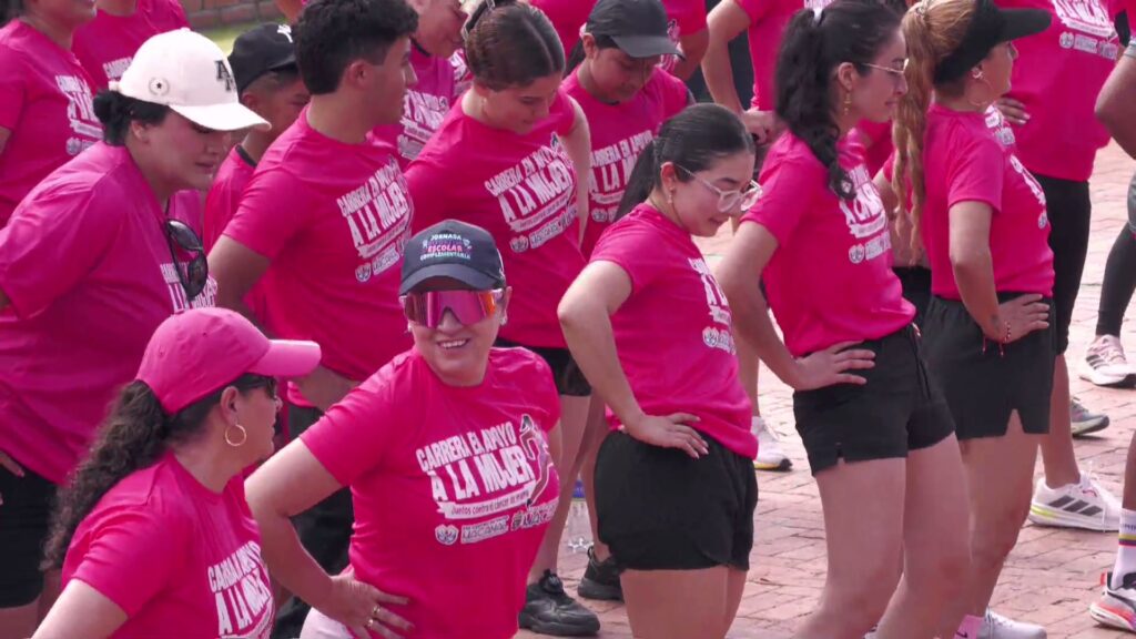 Mujeres con camisetas fucsia de la Carrera de la Mujer calientan en el parque principal de Macanal en el inicio del Festival del Agua