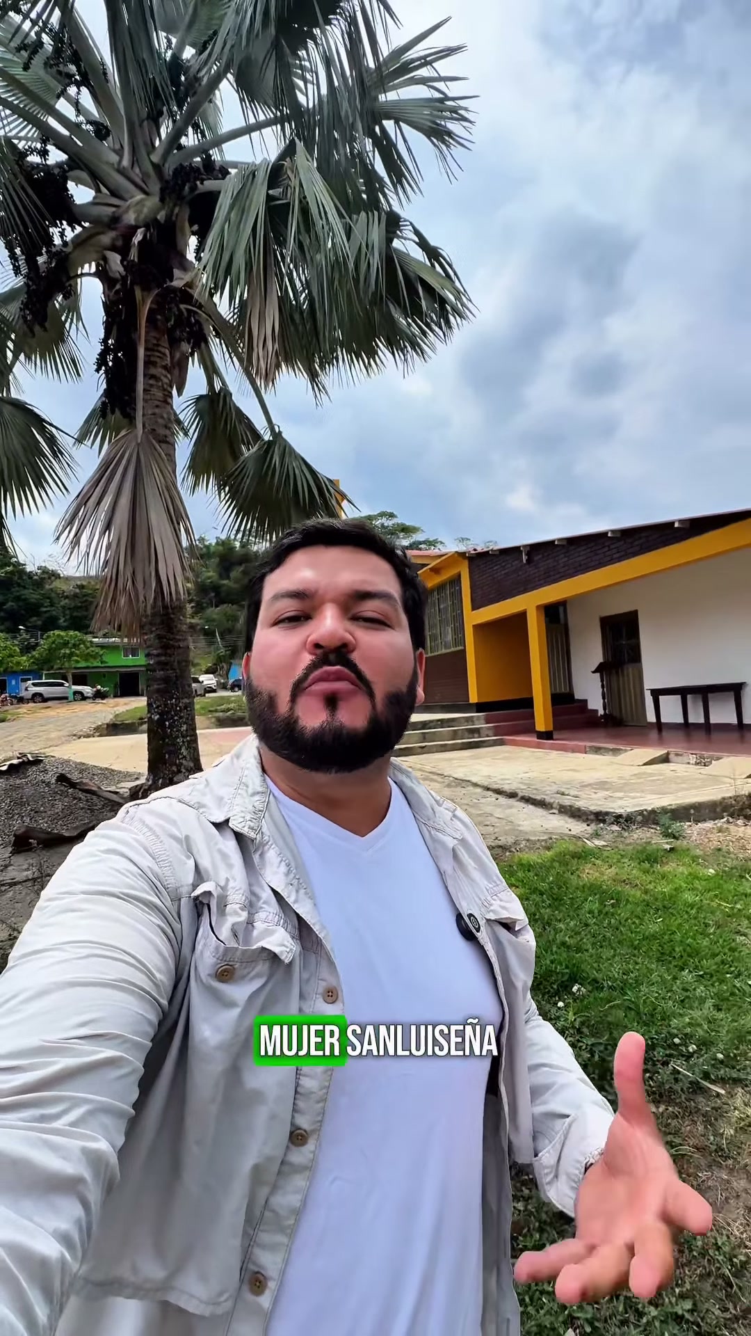 Hombre con barba se graba frente a una palmera en Horizontes, con el letrero «Mujer sanluiseña», en la invitación al festival equino y bovino