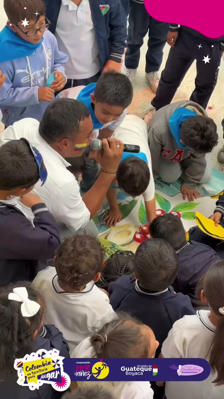 Niños rodean a un animador con micrófono en una actividad del Día de la Niñez en Guateque