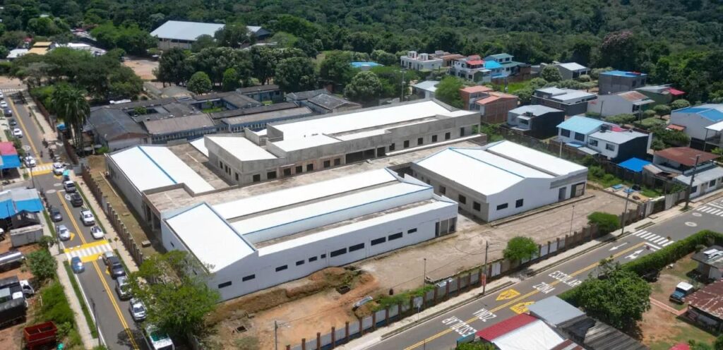 Vista aérea de los edificios de techo blanco del Hospital de Villanueva en construcción, junto a una calle del municipio