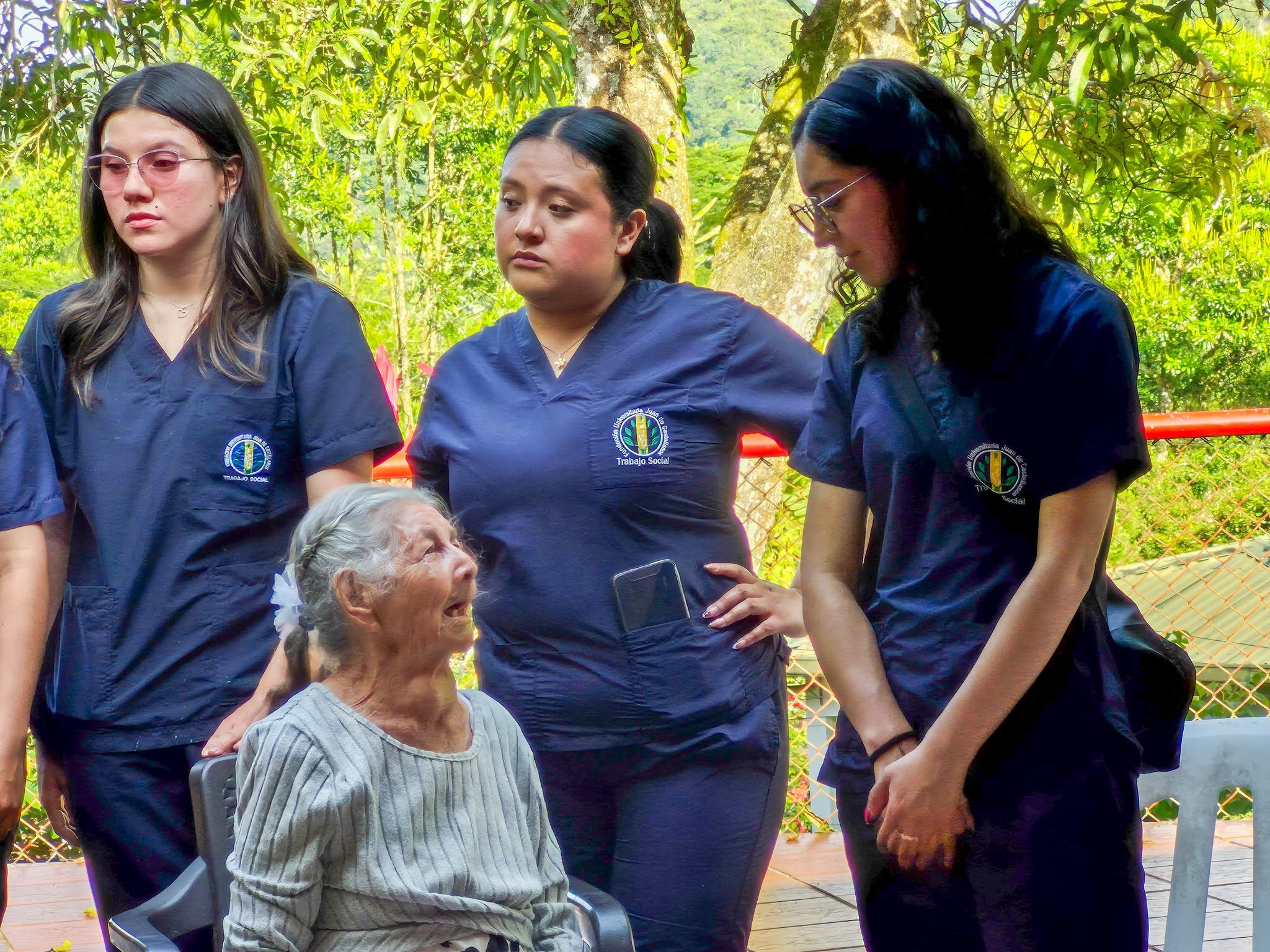 Una adulta mayor sonríe rodeada de tres estudiantes de Trabajo Social