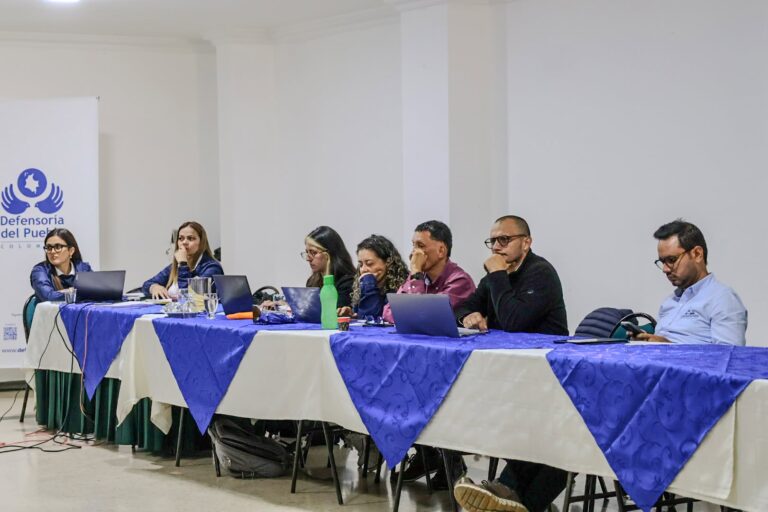 Funcionarias de la Defensoría del Pueblo y participantes sentados a una mesa con manteles azules en Tunja