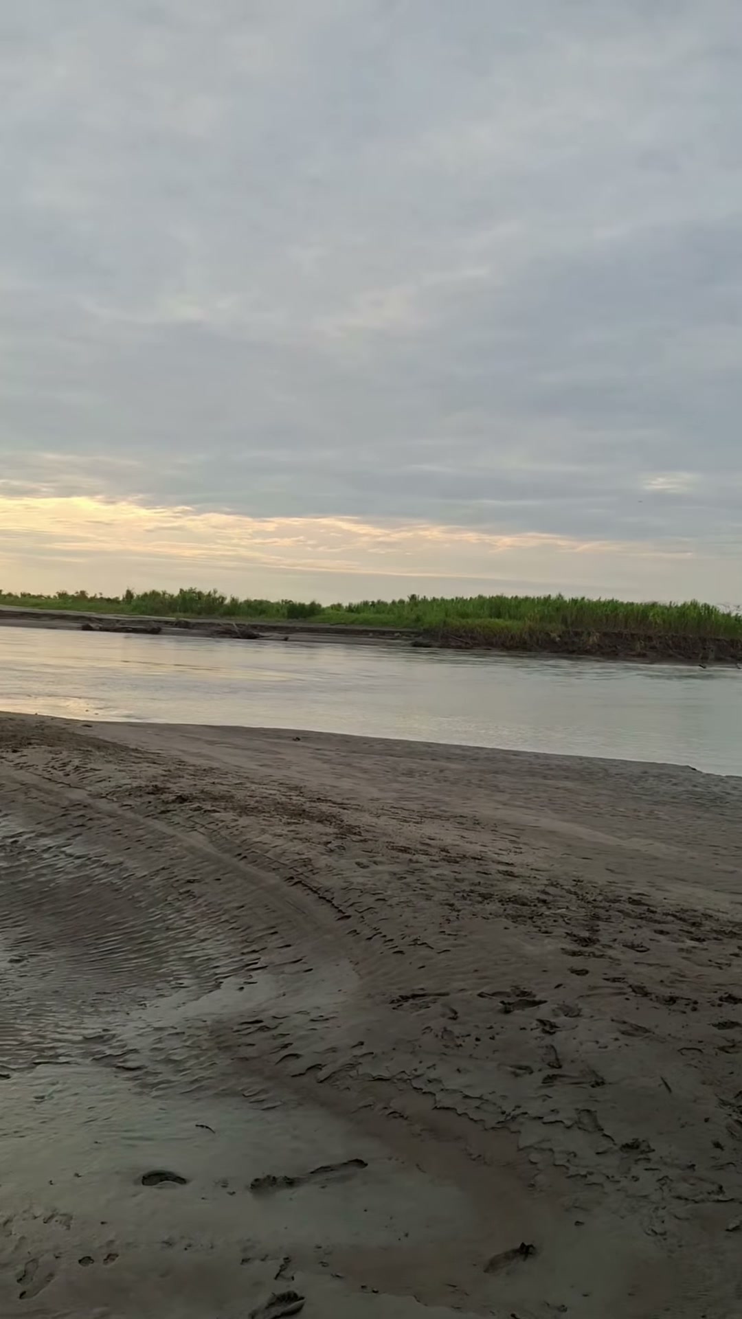 Orilla de arena húmeda y el río Upía con poca agua al atardecer, frente a Santa Helena de Upía