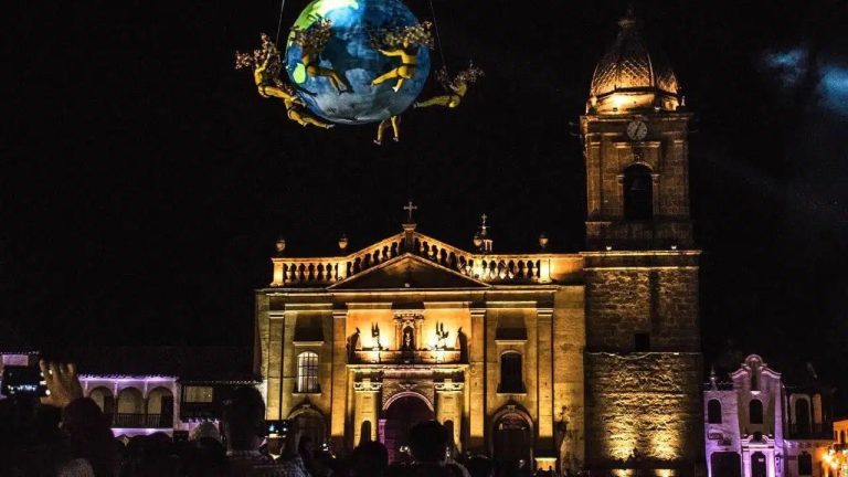 Acróbatas alrededor de un globo terráqueo frente a una iglesia colonial iluminada, en la Noche de Museos de Boyacá