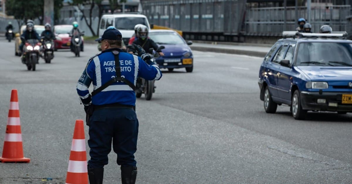 Un agente de tránsito de Bogotá dirige el paso de motos y carros en una avenida