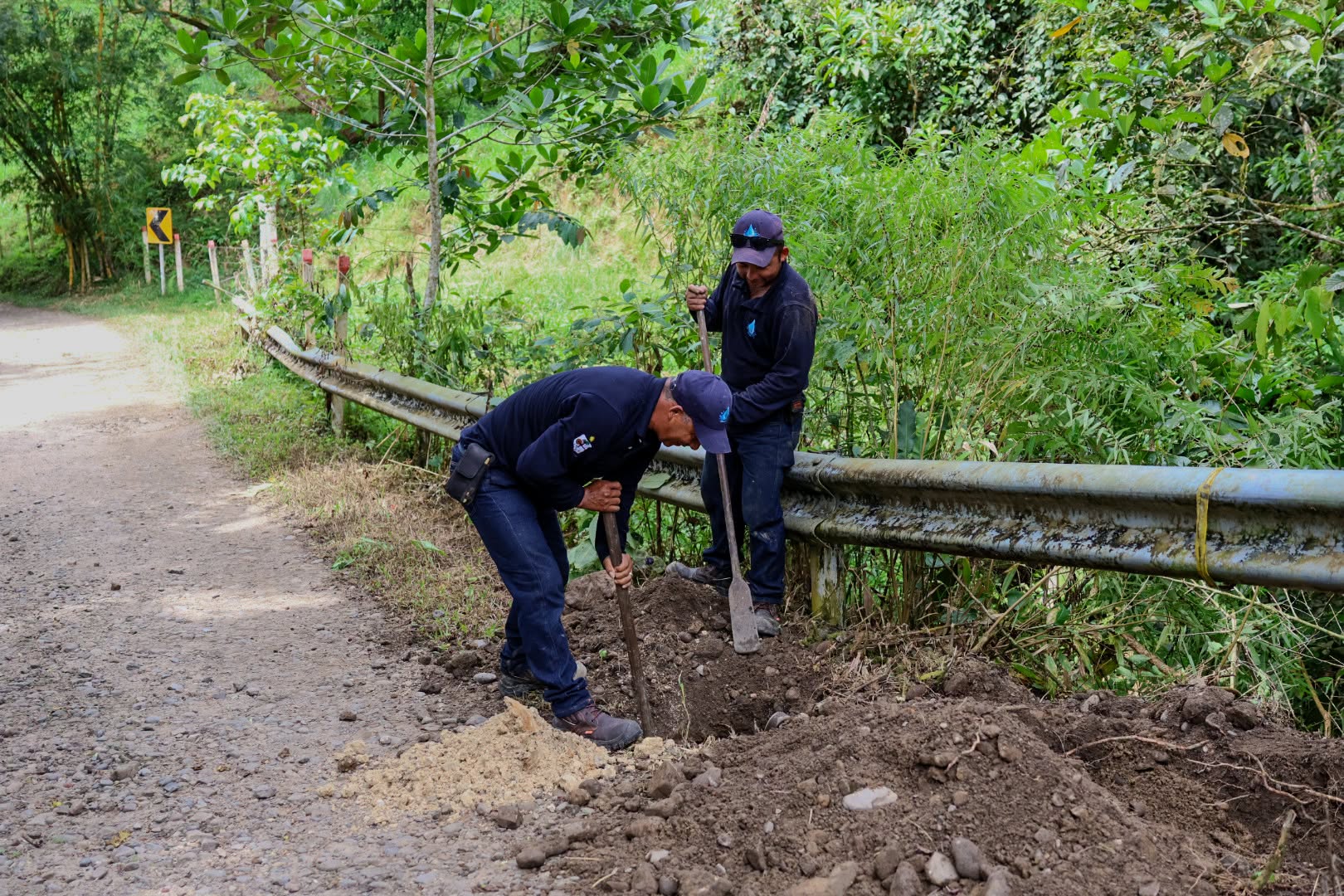 Dos trabajadores cavan junto a la baranda de la vía para ubicar la tubería del acueducto urbano de San Luis de Gaceno